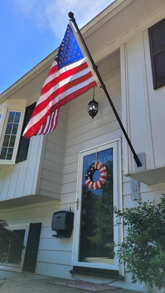 United States outdoor flag displayed on a house-mounted flagpole with mounting hardware