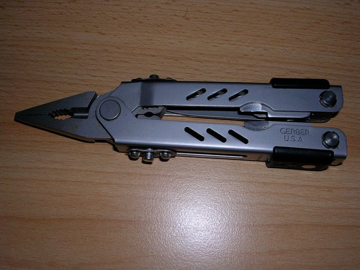Illustrative photograph of folding pliers-style multi-tool with metal handles, not a currently listed product