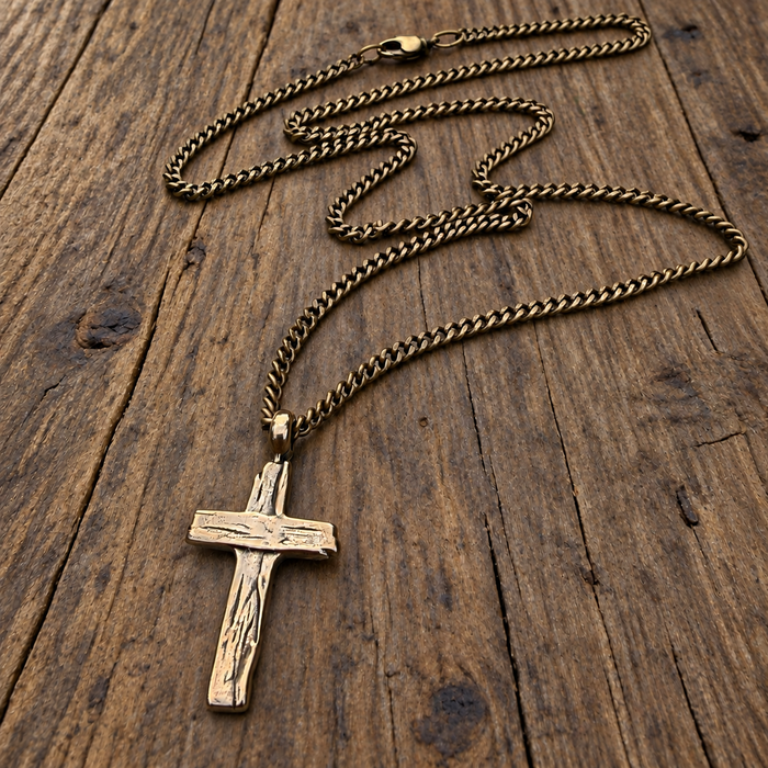 Weathered Cross necklace on curb chain against wood