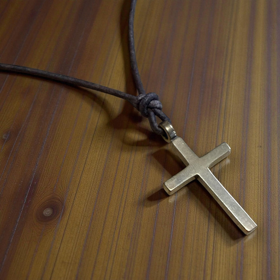 Classic cross and knotted leather cord against wood