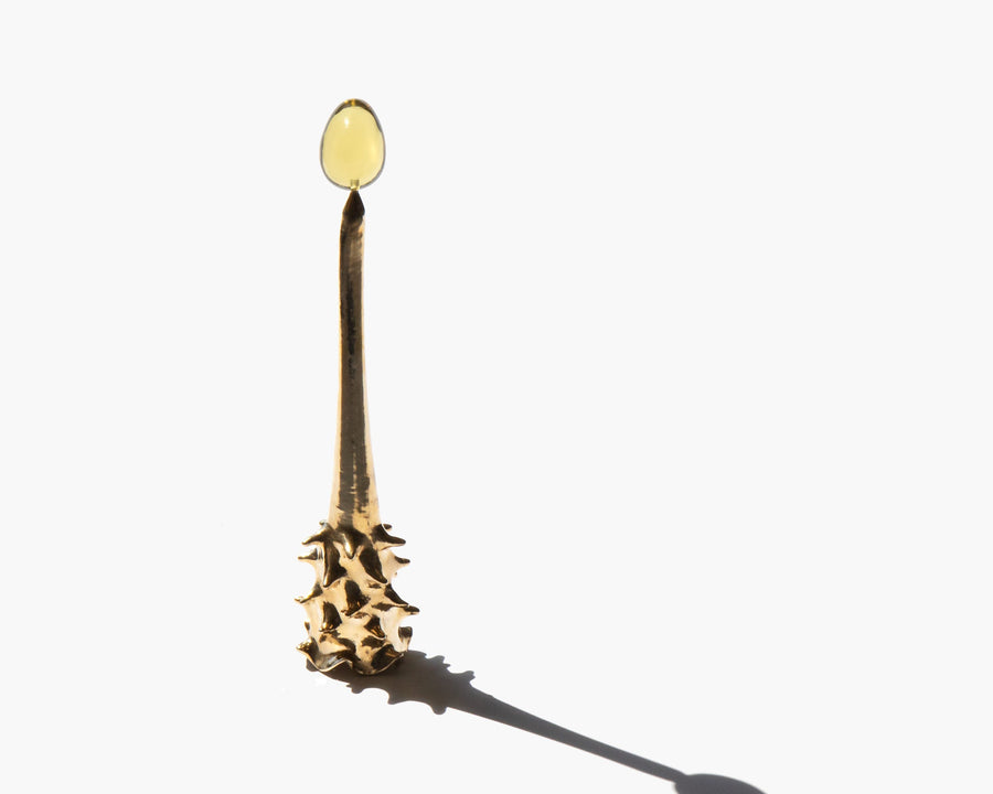 Brass Oracle snuffer with a long shadow on a pale surface