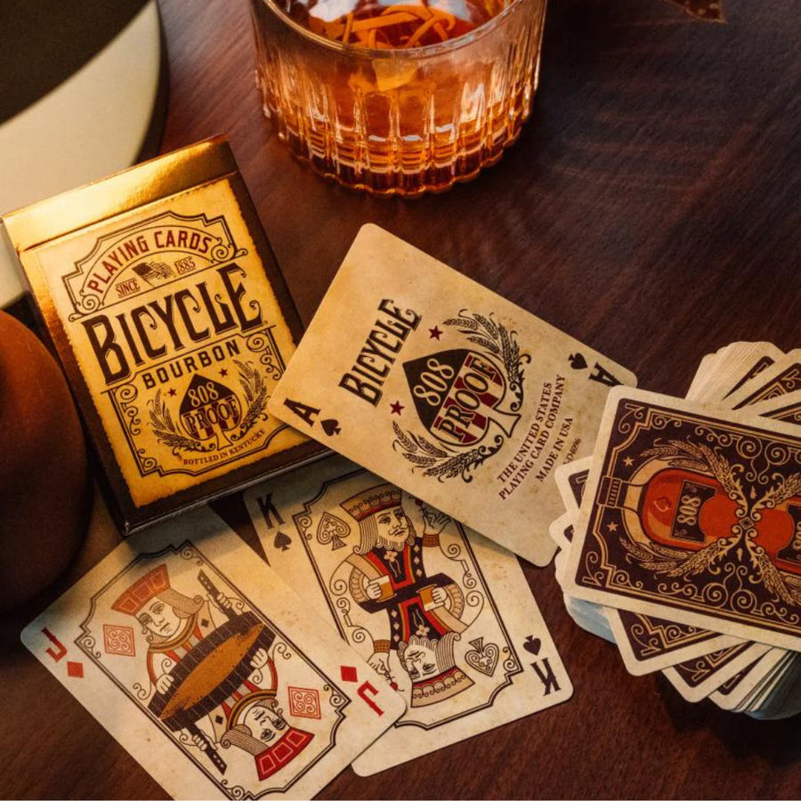 Bourbon-themed playing cards and tuck shown beside a drink