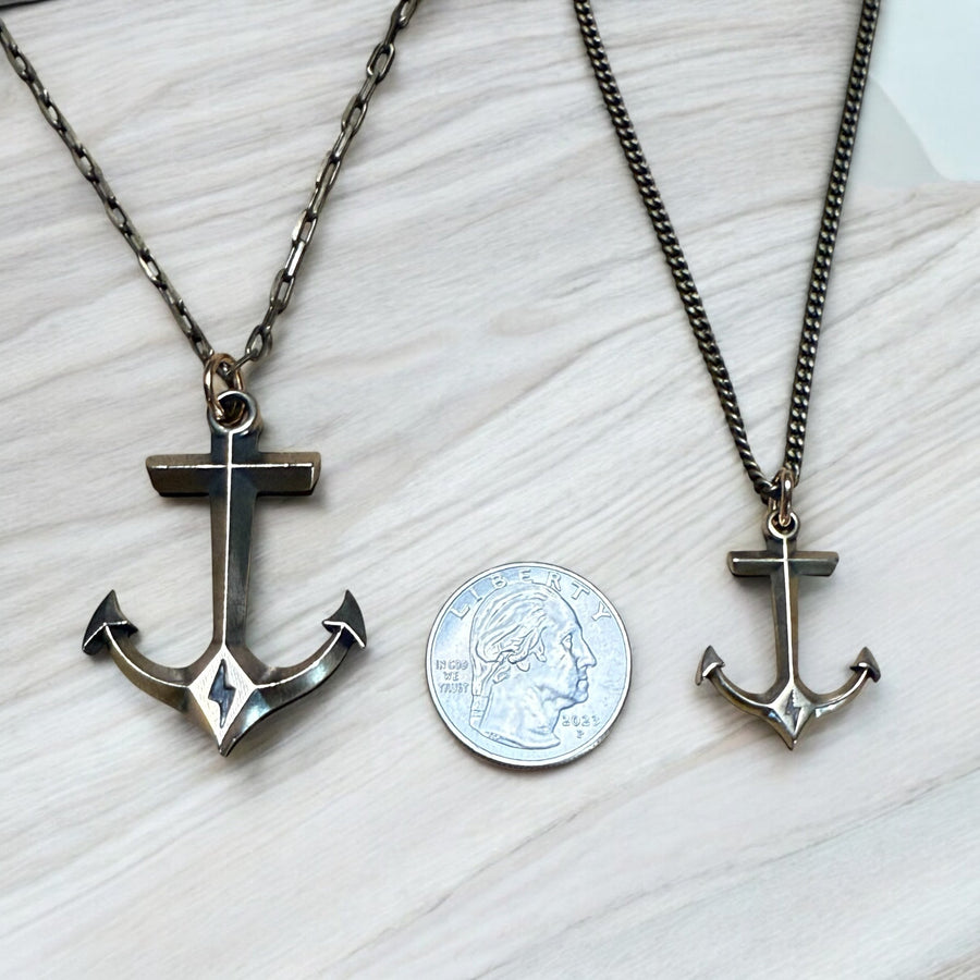 Large and small anchor pendants compared beside a coin