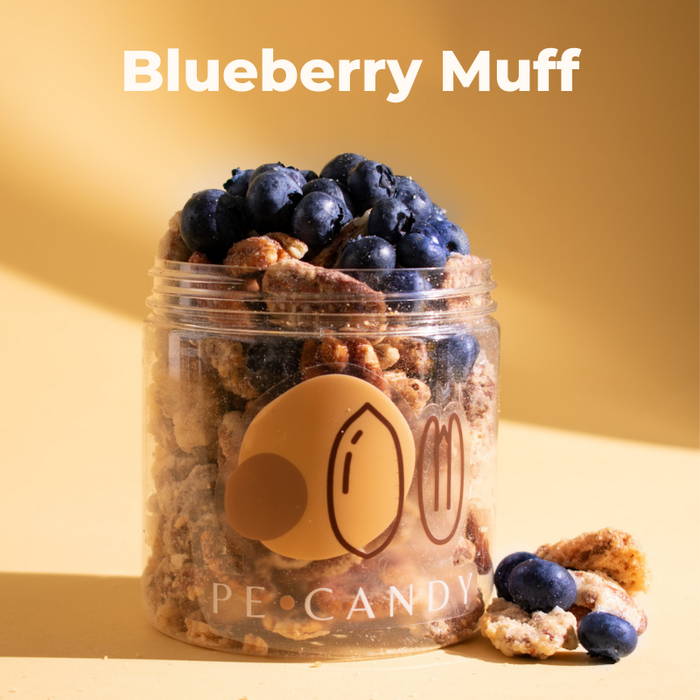 Blueberry Muff candied pecans in an open jar topped with blueberries and a muffin piece