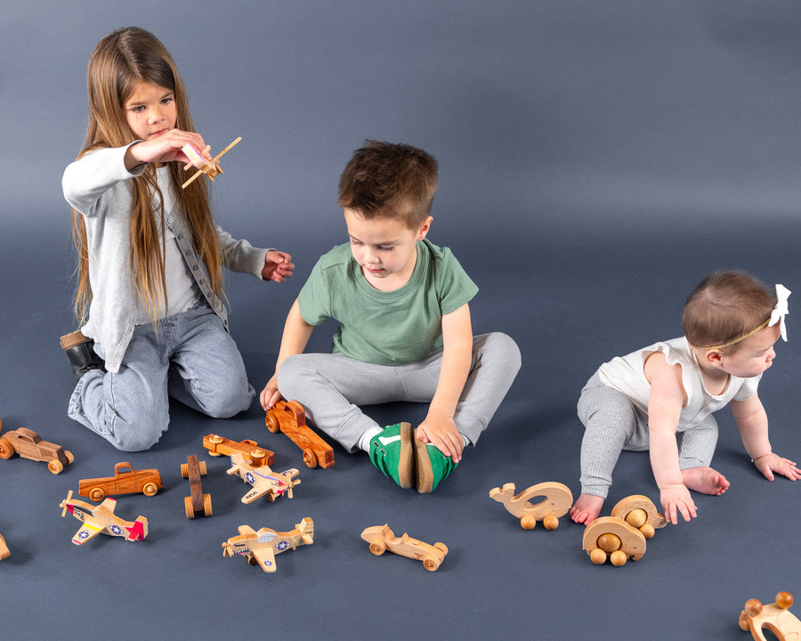 Children playing with an assortment of wooden cars, trucks and airplanes