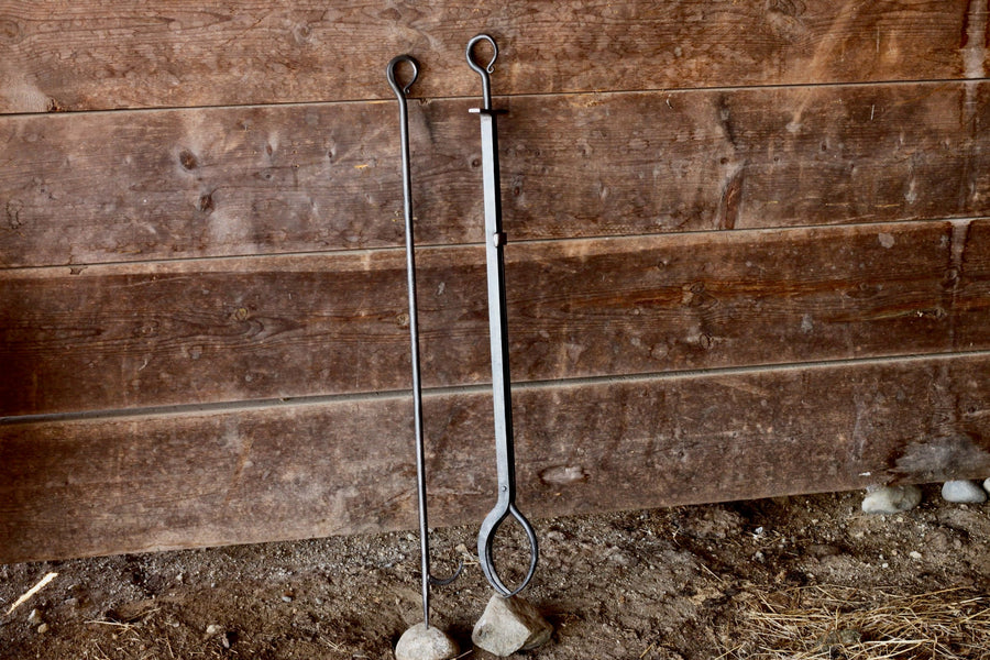 Heritage fire poker pictured beside fireplace tongs