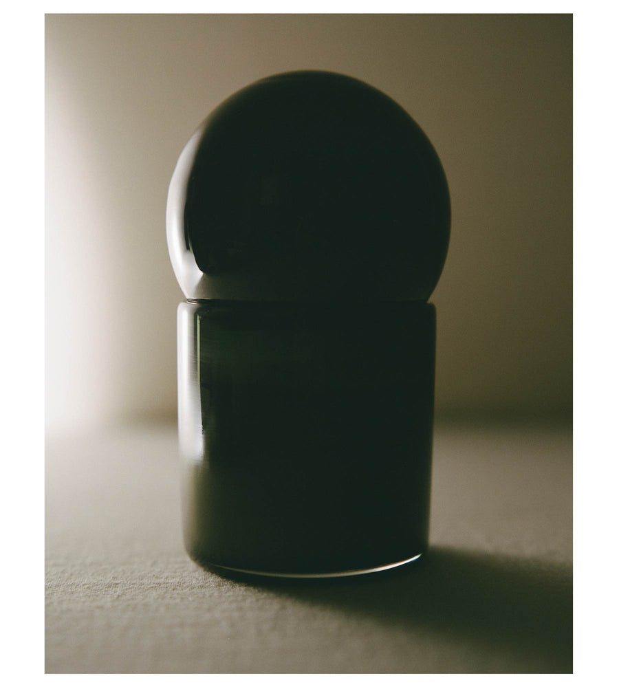 Orb candle in dark glass photographed in warm low light