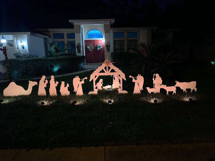 Outdoor nativity scene arranged across a lawn at night