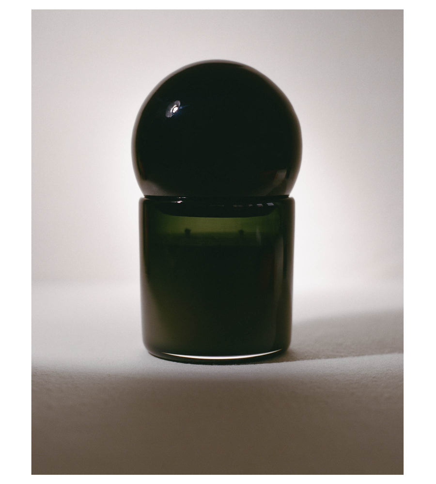Dark glass Orb candle in soft light with the lid in place