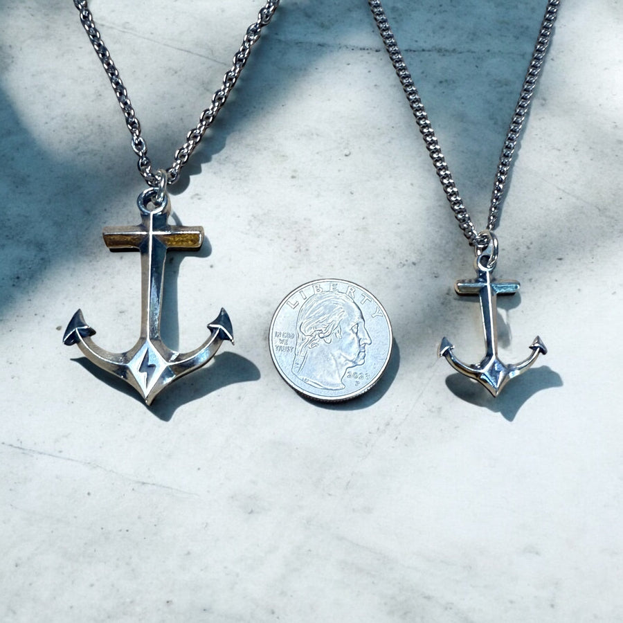 Large and small anchor pendants compared beside a coin