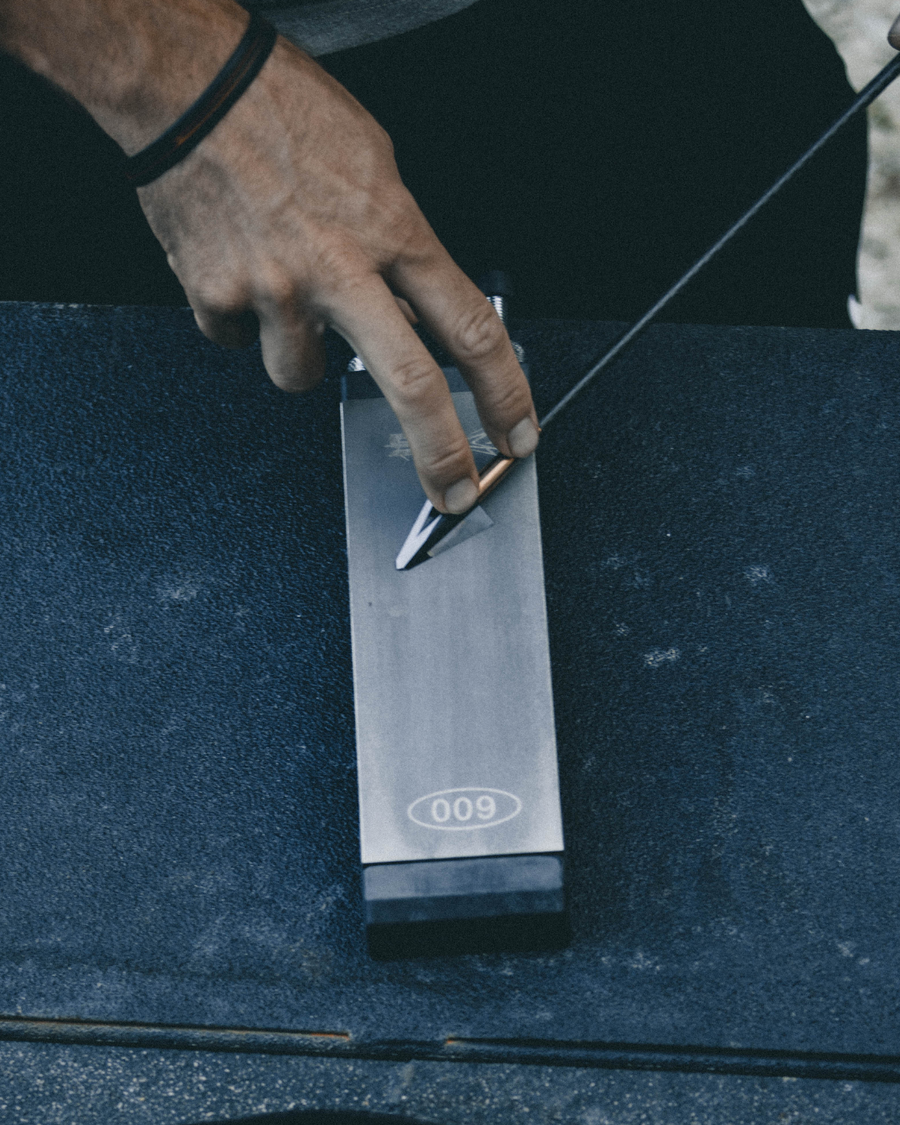 Broadhead being sharpened on a diamond stone outdoors