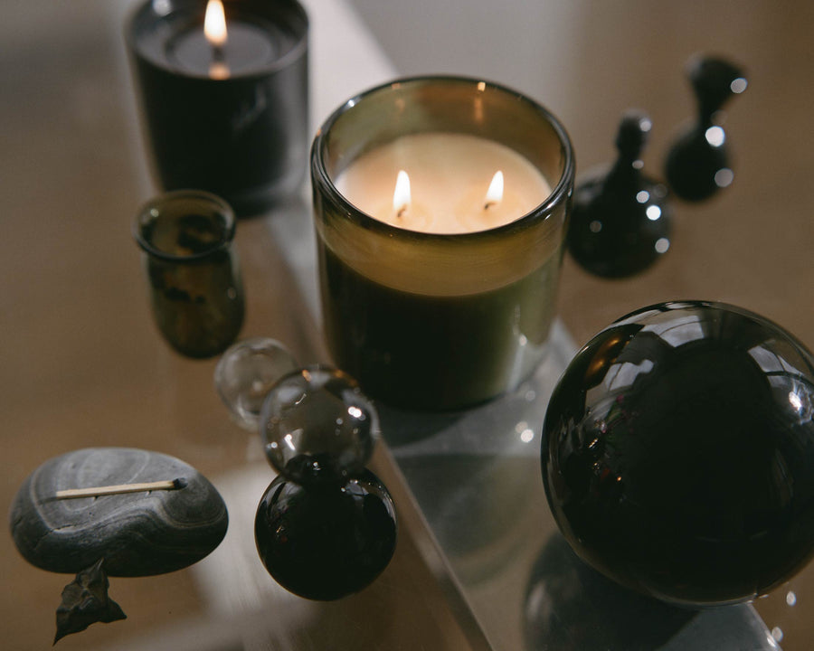 Two lit candles arranged with glass spheres and decorative objects