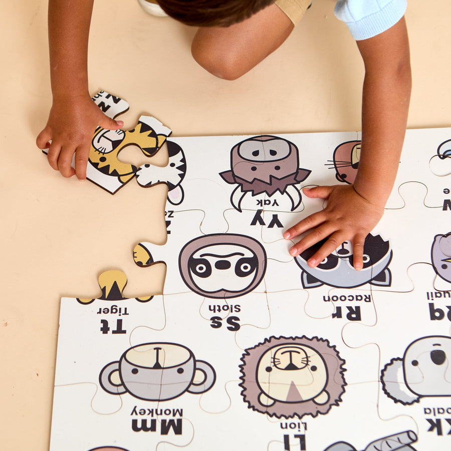 Child assembling an ABC animal floor jigsaw puzzle