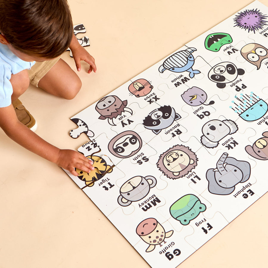 Child assembling an ABC animal floor jigsaw puzzle