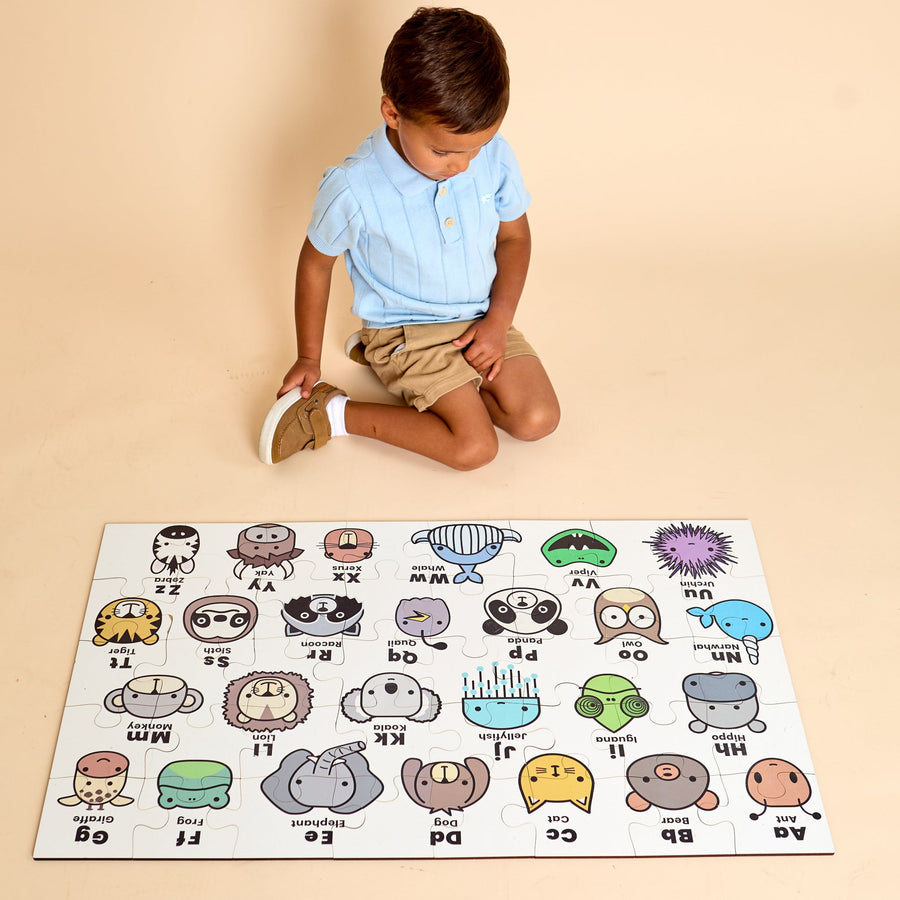 Child assembling an ABC animal floor jigsaw puzzle