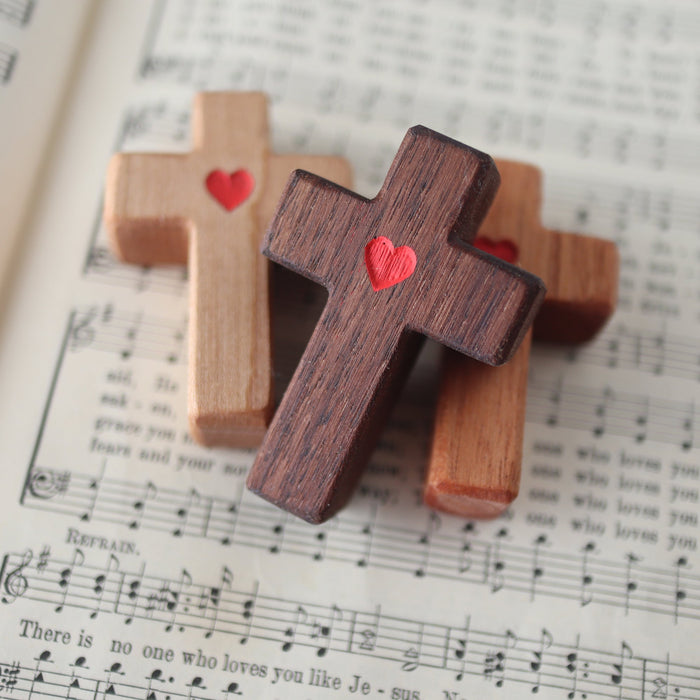 Wooden pocket crosses with small red heart engravings.