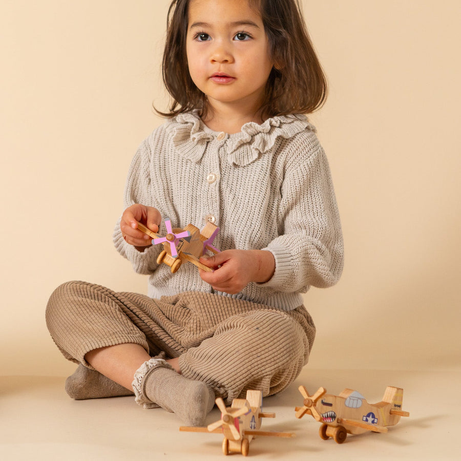 Child holding a wooden P-51-style toy airplane