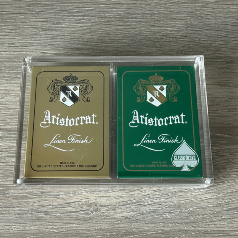 Gold and Currency Green Aristocrat decks displayed in a clear case