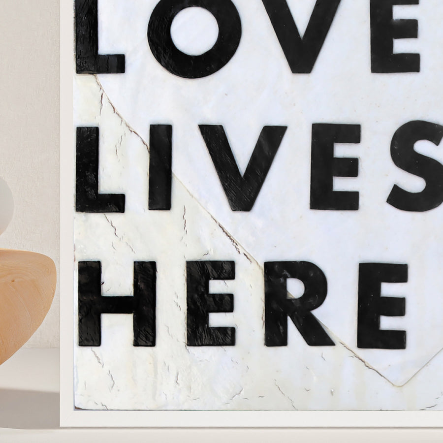 Love Lives Here art print with bold black lettering inside a heart outline.