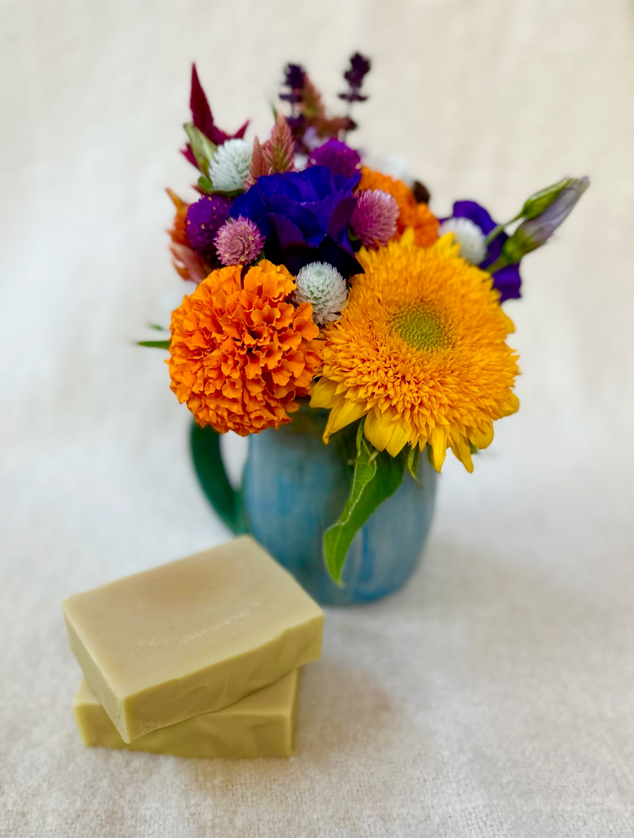 Unscented soap bars beside a vase of colorful flowers