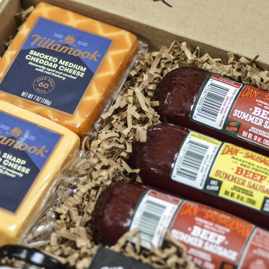 Close-up of Tillamook cheese and three wrapped summer sausages inside a Bare Necessities box
