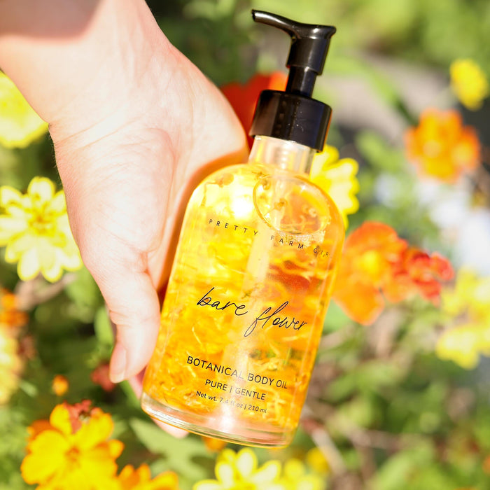 Hand holding Bare Flower body oil among garden flowers
