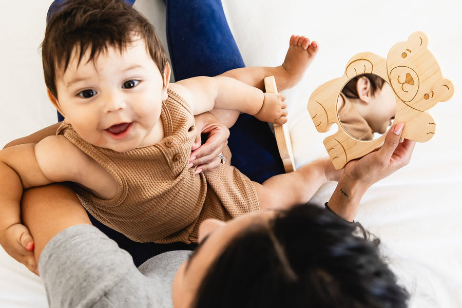 Child looking through a bear-shaped wooden discovery mirror