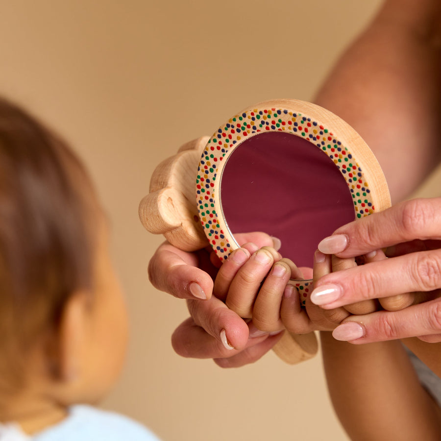 Child holding a round wooden-framed discovery mirror