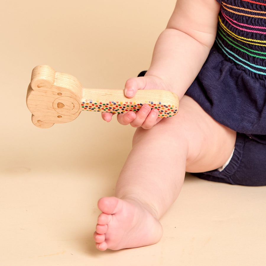 Close-up of a child’s hand holding a printed wooden rattle