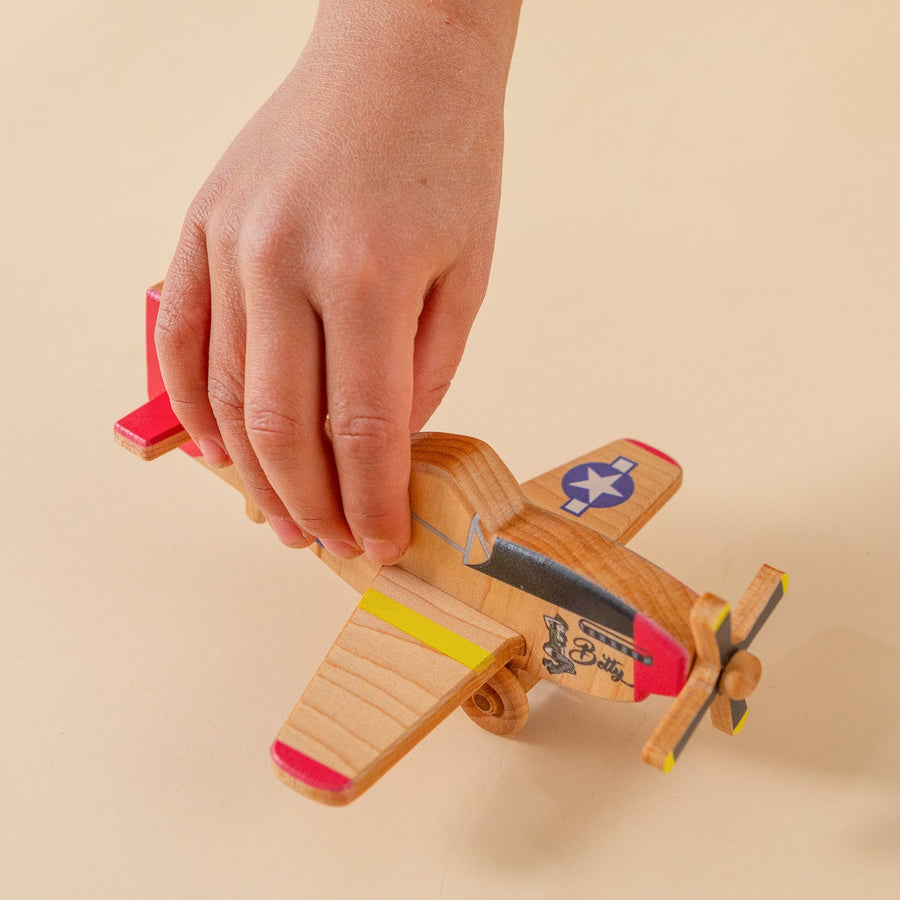 Child’s hands holding and guiding a wooden toy airplane