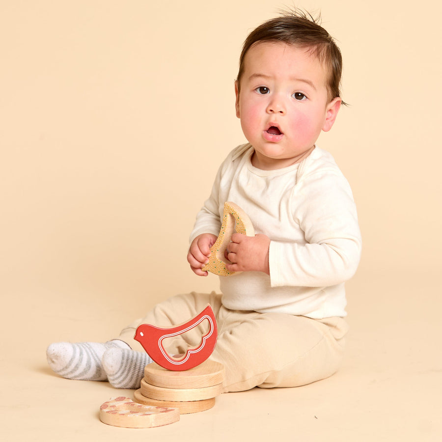 Baby holding a bird-shaped wooden rattle and teether