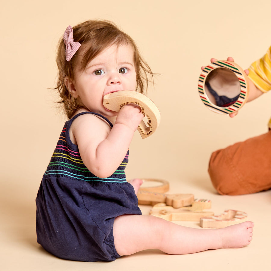 Child grasping and exploring a bird-shaped wooden rattle
