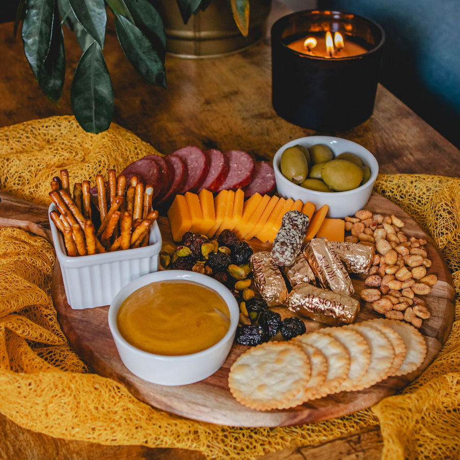 Sausage, cheese, crackers, pretzels, nuts, olives and mustard arranged on a platter; serving suggestion