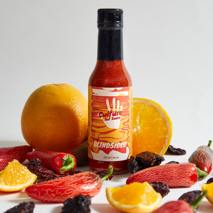 Blindsided hot sauce bottle with oranges and red chilies