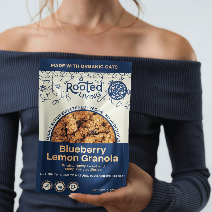 Person holding an 8 oz pouch of Rooted Living Blueberry Lemon Granola