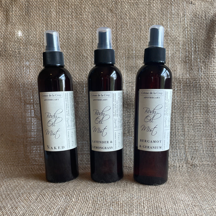 Three botanical body oil mist bottles with spray tops