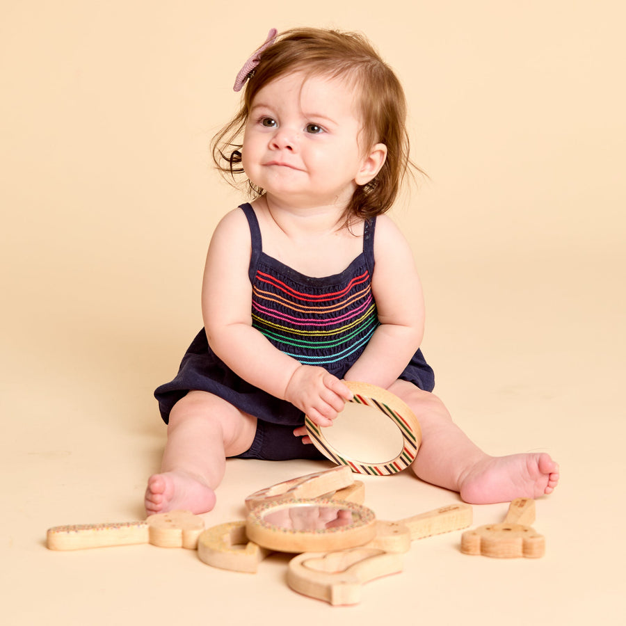 Child holding a round wooden-framed discovery mirror
