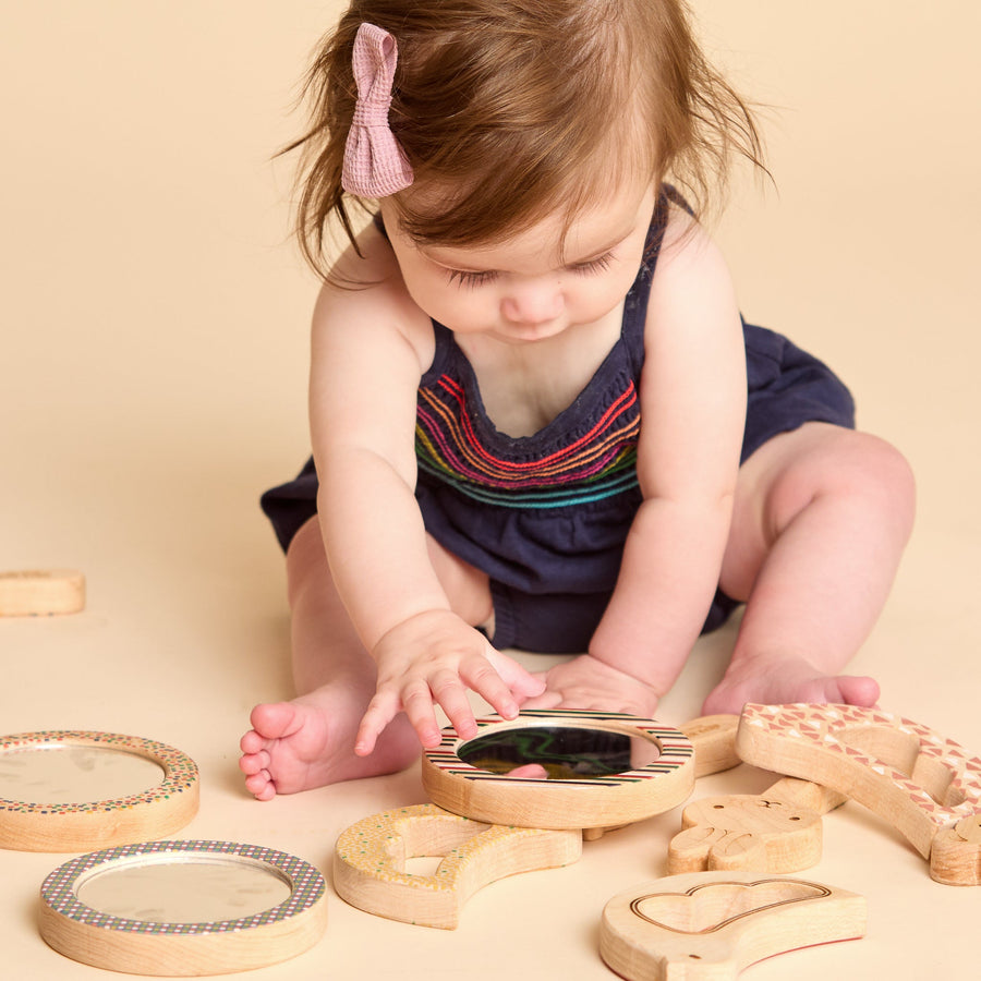 Child holding a round wooden-framed discovery mirror