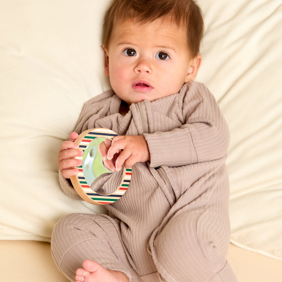 Child holding a round wooden-framed discovery mirror