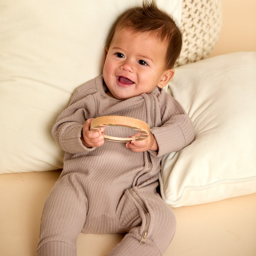 Baby holding a wooden animal-shaped rattle during supervised play