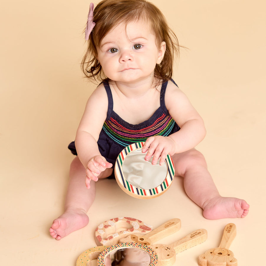 Child holding a round wooden-framed discovery mirror