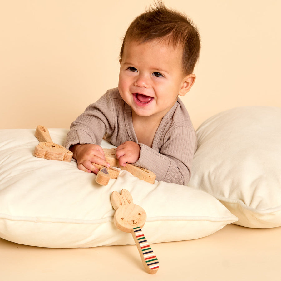 Baby holding a wooden animal-shaped rattle during supervised play