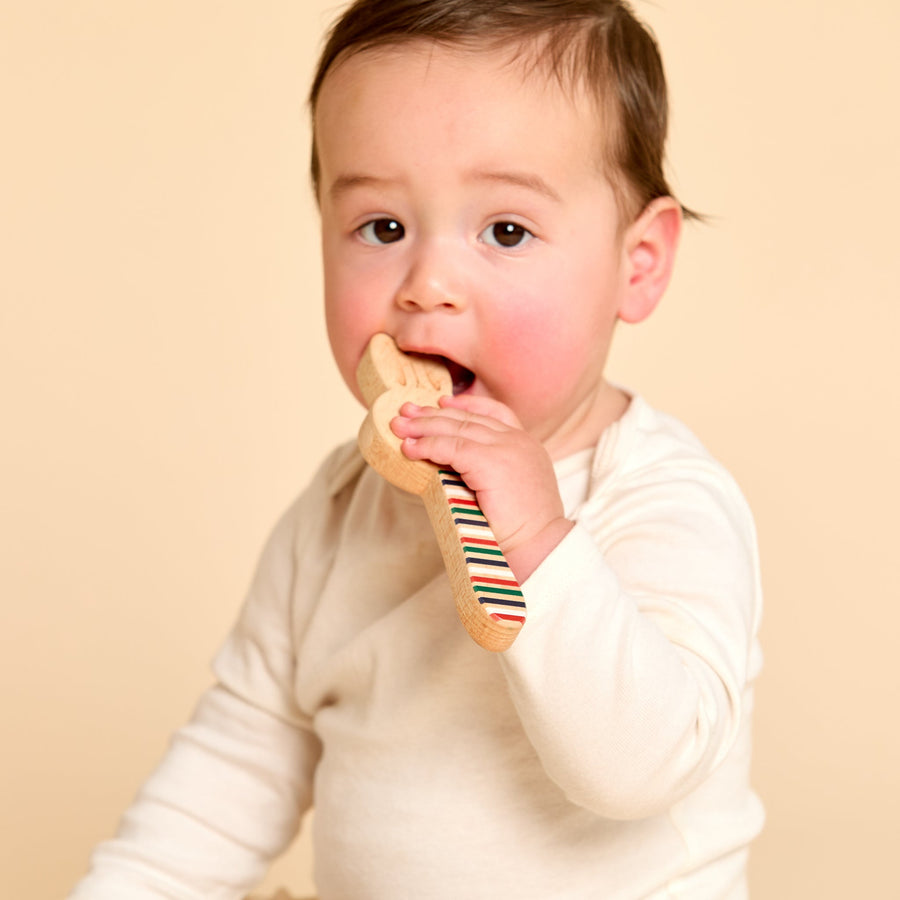 Baby holding a wooden animal-shaped rattle during supervised play