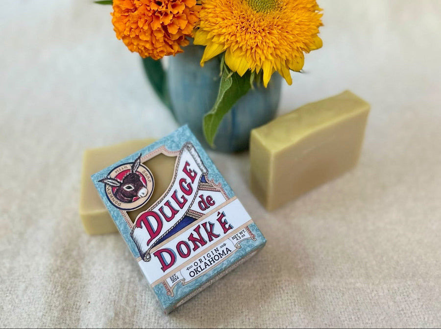 Unscented soap bars and branded box beside orange and yellow flowers
