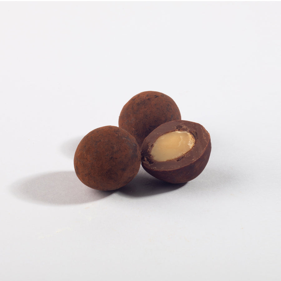 Toffee Milk Chocolate Macadamia Nuts, whole and halved to show the nut center