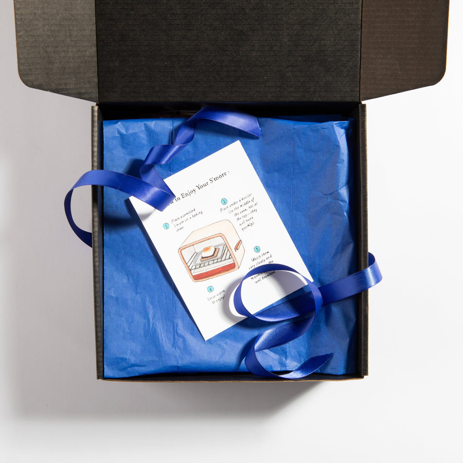 Open black smores gift box with blue ribbon and product card