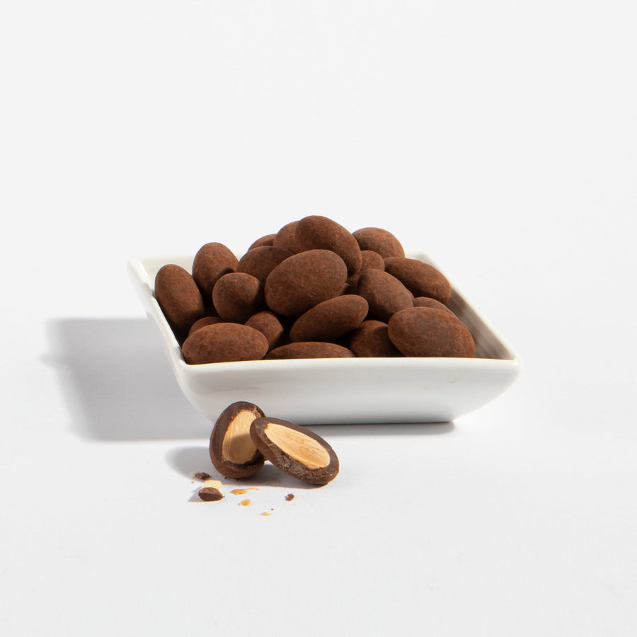 Triple Chocolate Almonds in a serving dish with one almond cut open