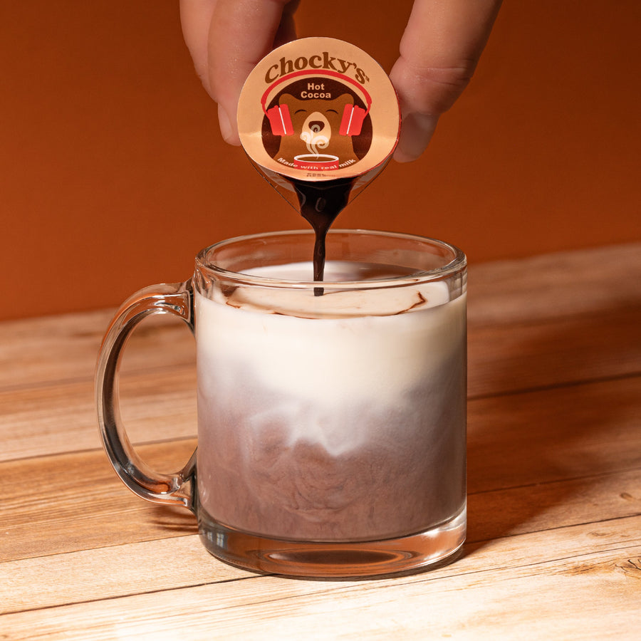 Hand pouring a cocoa pod into a mug