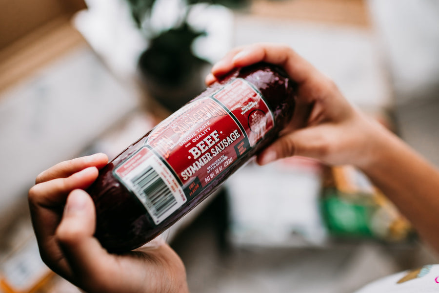 Hands holding a wrapped beef summer sausage with a red label
