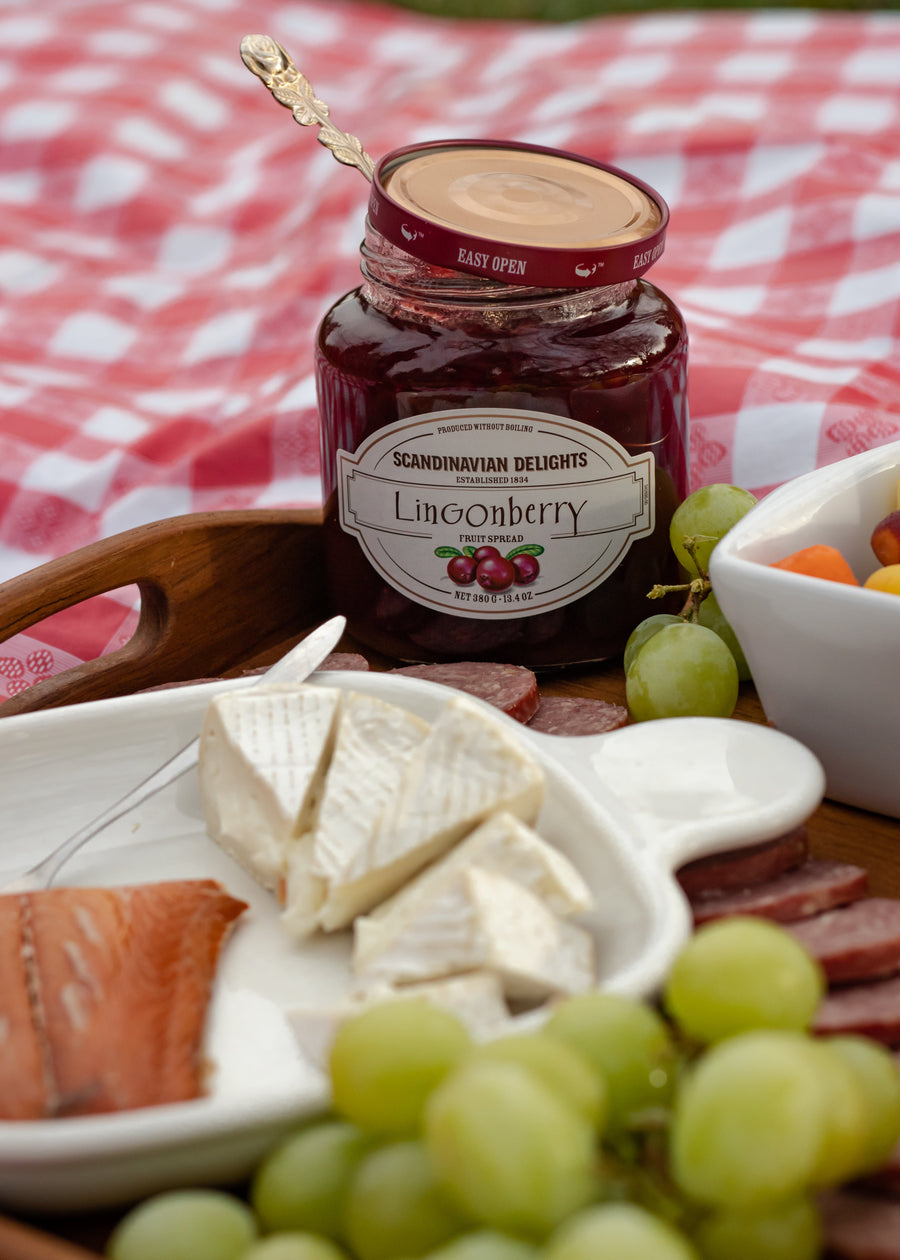 Lingonberry spread jar beside a plate of cheese and grapes; serving suggestion